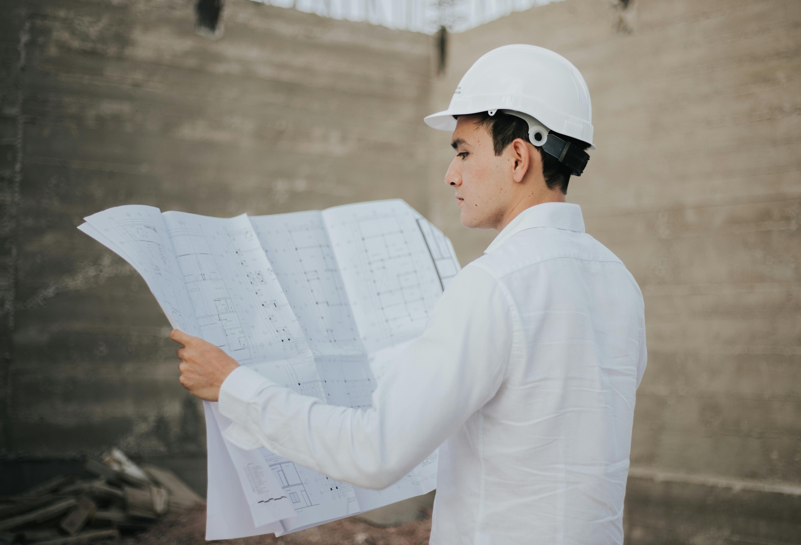 Tacoma Commercial General Contractor Person reviewing construction plans outdoors.